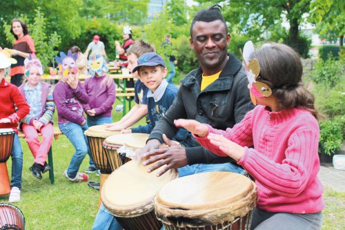 Trommeln macht Spaß, vor allem wenn Jack Panzo (Bildmitte) den Rhythmus vorgibt. Der aus Angola stammende Künstler war am 6. Mai Gast beim Frühlingsfest im Bürgergarten am Koitschgraben der gleichnamigen Kontaktstelle in Strehlen. Foto: Stadtteilbüro am Koitschgraben