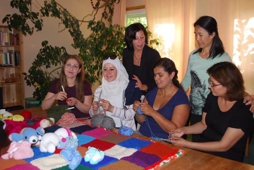 Beim Stricken kommen sie schnell ins Gespräch: Lara aus Syrien (l.), Annelie Gunkel (hinten stehend links) und die anderen Frauen aus Syrien, Paraguay, China und Afghanistan. Foto: Trache