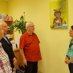 Künstlerin Ramona Hellmann (im Bild rechts) im Gespräch mit Besuchern ihrer Vernissage. Im Hintergrund ist das BIld der Künstlerin Die Naschkatze zu sehen. Foto: Steffen Dietrich