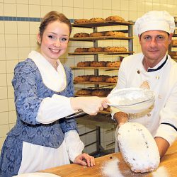 Und noch eine Prise Puderzucker mehr: Das Stollenmädchen sorgt für die süße Vollendung des Weihnachtsgebäcks, das Tino Gierig gut festhält. Foto: Pohl