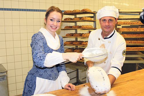 Und noch eine Prise Puderzucker mehr: Das Stollenmädchen sorgt für die süße Vollendung des Weihnachtsgebäcks, das Tino Gierig gut festhält. Foto: Pohl