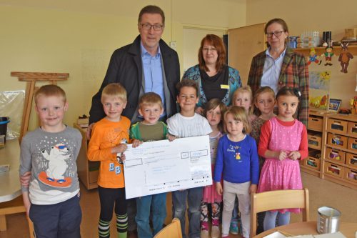 Einen dicken Scheck hatte Ernst Kötter von der Stiftung »Zukunft schützen« im Gepäck. Kita-Leiterin Mandy Langer und die Leiterin des städtichen Eigenbetriebs Sabine Bibas (v. l.) freuen sich mit den Kids. Foto: Möller