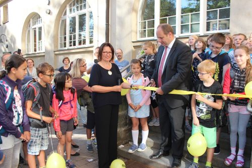 Anlässlich der eröffnung des Tolkewitzer Gymnasiums durchschneidet Oberbürgermeister Dirk Hilbert das Band am hinteren Eingang der Sieben-Schwaben-Schule. Die Schulleiterin Dr. Ulrike Böhm assistiert ihm, Grundschüler und Gymnasiasten schauen aufmerksam zu. Foto: Pohl