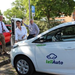 E-Tankstelle auf dem Parkplatz in Gruna: Constanze Krampe lädt eins ihrer Fahrzeuge an der neuen Ladestation. Im Hintergrund: Dr. Hans-Peter Klengel, Vorstand der WG Aufbau, und Swen-Sören Börner von der DREWAG. Foto: Pohl