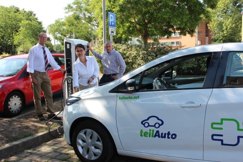 E-Tankstelle auf dem Parkplatz in Gruna: Constanze Krampe lädt eins ihrer Fahrzeuge an der neuen Ladestation. Im Hintergrund: Dr. Hans-Peter Klengel, Vorstand der WG Aufbau, und Swen-Sören Börner von der DREWAG. Foto: Pohl