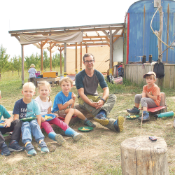 Natur entdecken macht hungrig. Bei sommerlichen Temperaturen stärken sich die Kinder mit Schnitzel und Kartoffeln auf dem „Waldsofa“ vor ihrer „Basisstation“ – einem Bauwagen. Foto: Steffen Dietrich