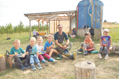 Natur entdecken macht hungrig. Bei sommerlichen Temperaturen stärken sich die Kinder mit Schnitzel und Kartoffeln auf dem „Waldsofa“ vor ihrer „Basisstation“ – einem Bauwagen. Foto: Steffen Dietrich