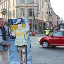 Günther Jakob dirigierte jahrelang am Schillerplatz den Verkehr. Daran erinnert ein lebensgroßes Bild. Am 26. Oktober 2018 kehrte der Ruheständler noch einmal an den Ort des Geschehens zurück, denn sein Bild wurde an den Polizeipräsidenten Horst Kretzschmar übergeben. Es erhält nun einen würdigen Platz im Polizei-Museum. Für eine halbe Stunde übernahmen Polizeibeamte die Verkehrsregelung. Foto: Pohl