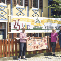 Jana Körner (r.) präsentiert mit Vorstandsmitglied Barbara Jäger und Irene Richter das über 20 Meter lange Transparent, auf das bunte Stoff­hände aufgenäht wurden. Es wird das Putjatinhaus schmücken. Foto: CT