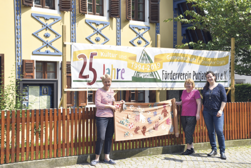 Jana Körner (r.) präsentiert mit Vorstandsmitglied Barbara Jäger und Irene Richter das über 20 Meter lange Transparent, auf das bunte Stoff­hände aufgenäht wurden. Es wird das Putjatinhaus schmücken. Foto: CT