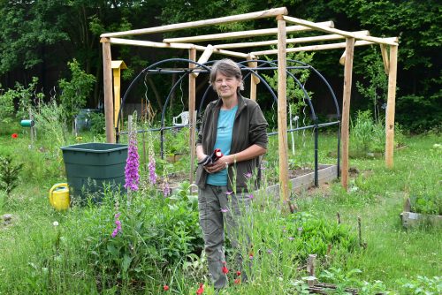 Heike Löffler mitten im blühenden Garten vor dem fast fertigen Tomatenhaus. Foto: Trache