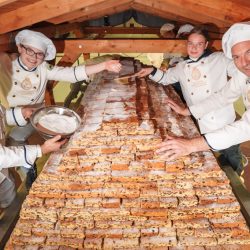 Der Riesenstollen wurde am 30. November zusammengebaut. Mit dabei waren Torsten Richter und Johanna Meitzner (linke Seite), Lina Hoffmann und Dirk Willkomm (rechte Seite). Am 6. Dezember wird der Striezel nach dem Festumzug portionsweise verkauft. Foto: Schutzverband Dresdner Stollen e.V./Michael Schmidt